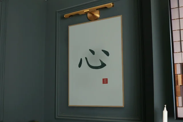 Cœur à l'encre, jade : affiche encadrée chêne sous une lampe de tableau, mur vert profond