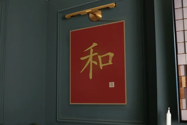 Harmonie à l'encre, laque rouge : affiche encadrée chêne sous une lampe de tableau, mur vert profond