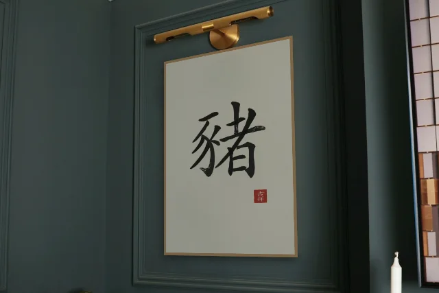 Signe du Cochon à l'encre, papier xuan : affiche encadrée chêne sous une lampe de tableau, mur vert profond