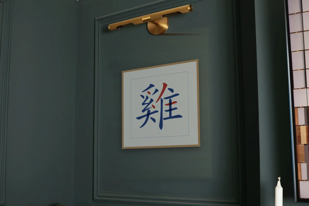 Signe du Coq en aplats, porcelaine bleue. Photo d'illustration : Affiche encadrée chêne sous une lampe de tableau, mur vert profond, œuvre en 50 × 50 cm, à l'échelle. Photo de la pièce : Paul Yarnell (Unsplash).