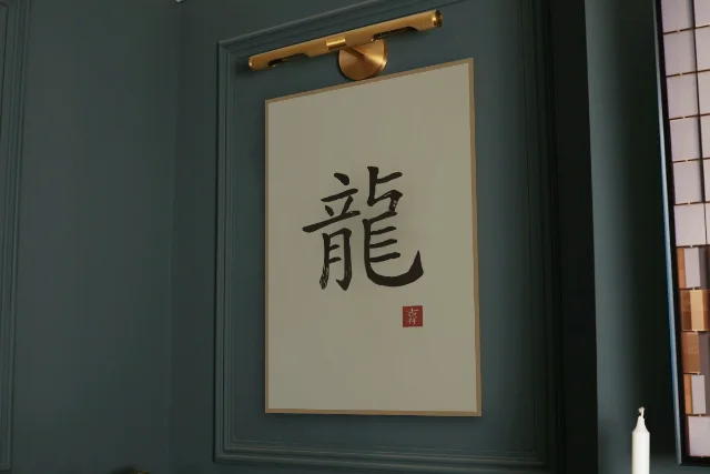 Signe du Dragon à l'encre, sable ocre : affiche encadrée chêne sous une lampe de tableau, mur vert profond